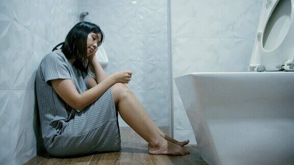 悲伤的女人坐在浴室地板上怀孕测试呈阴性