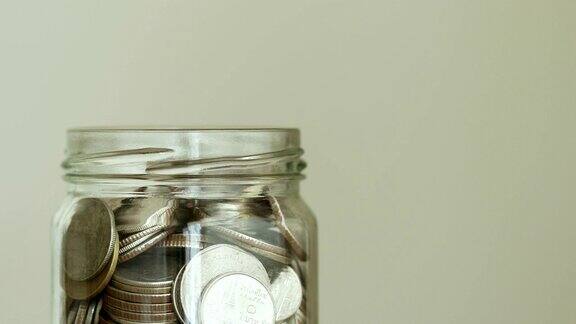 硬币落入玻璃罐省钱捐赠或企业财务增长概念4KDci分辨率