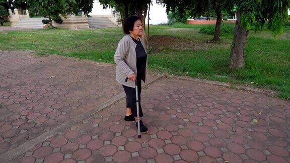 老妇人拄着拐杖在公园散步的慢镜头