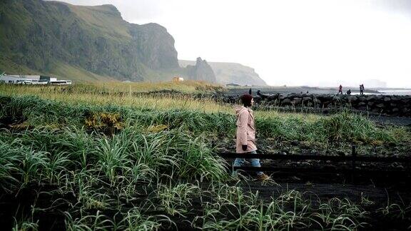 一名女子走在冰岛维克的黑色沙滩上