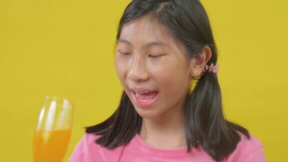 亚洲女孩吃巧克力甜甜圈在黄色背景慢动作