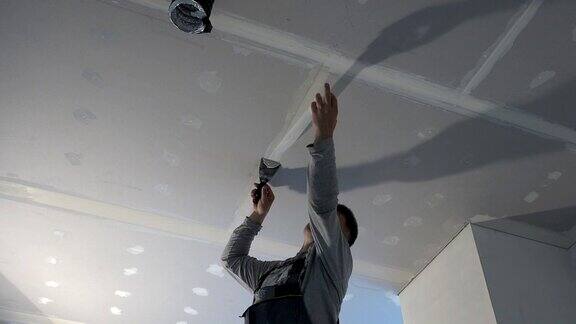 工人将玻璃纤维胶带粘在天花板石膏板上