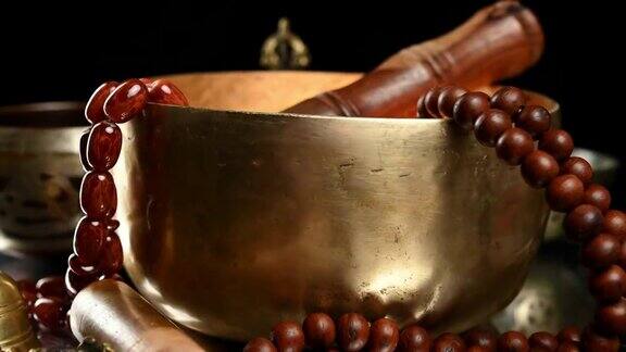 在棕色的木桌上放着一个带拍子的西藏唱歌铜碗是用来冥想和替代医学的物品