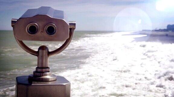 光学耀斑镜头的旅游望远镜在海边与汹涌的海浪