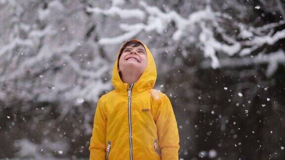 穿着黄色冬衣的滑稽小男孩在下雪时行走儿童冬季户外活动