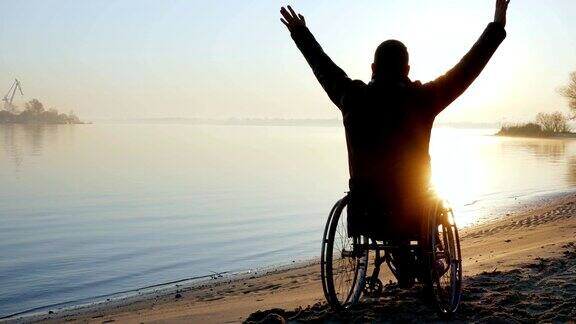 残疾人坐在轮椅上举起双手夕阳西下孤独残疾人上