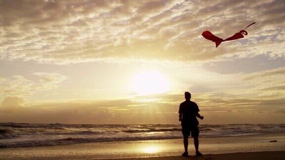 男性在户外放玩具风筝的剪影日落