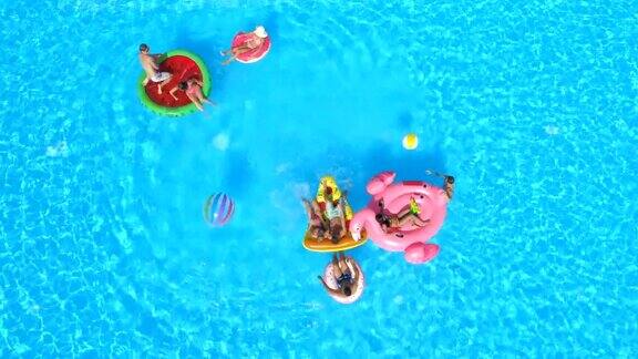 图片:年轻人在游泳池里玩五彩缤纷的充气浮子