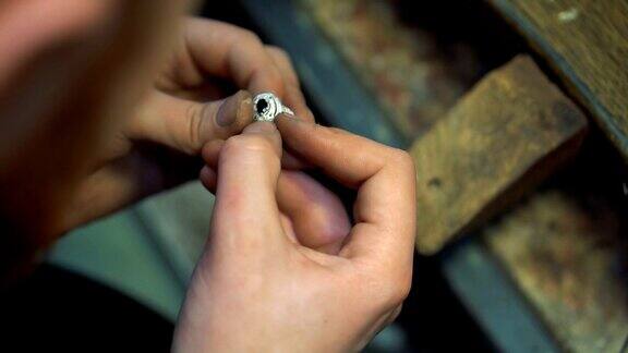 珠宝商手里拿着一枚成品银戒指继续打磨