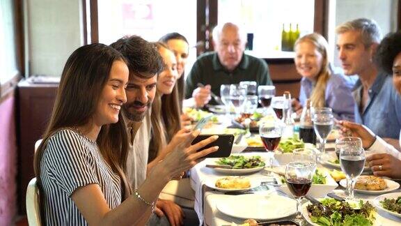 一名女子在餐厅与家人共进午餐时在手机上展示照片