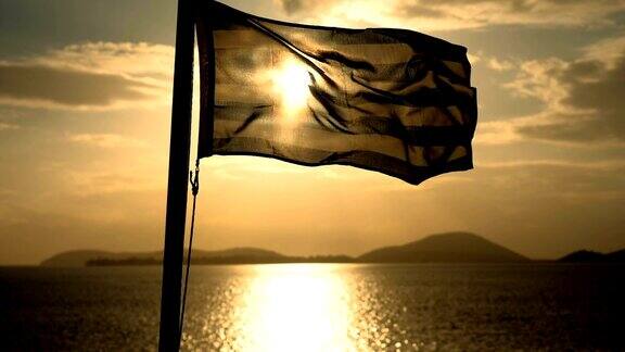 黄昏时分在海上航行的船只上飘扬着希腊国旗缓慢的运动高清