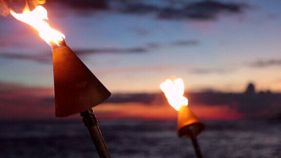 夏威夷考艾岛日落热带海滩上的火炬燃烧