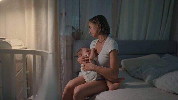 年轻漂亮的母亲在昏暗的灯光下给刚出生的男婴喂奶妈妈母乳喂养婴儿