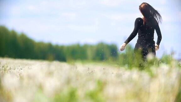 在阳光明媚的日子里年轻女子从蒲公英草地上跑出来的背影