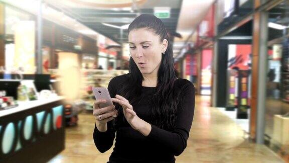 迷人的黑发女子惊讶地在智能手机上阅读信息