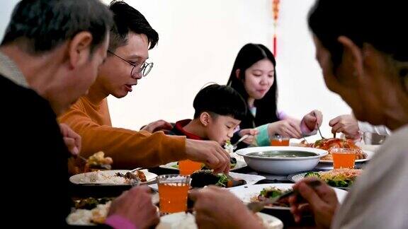 在中国新年期间快乐的亚洲家庭的三代人在家里庆祝和享受团圆饭