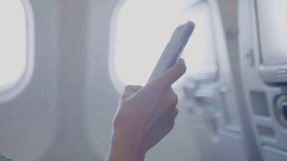 一名亚洲女性在飞机上使用智能手机