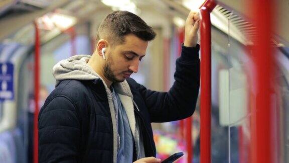 年轻人在地铁里打电话用智能手机玩游戏用手机发短信用手机浏览社交媒体用一只手玩游戏戴着耳机听音乐