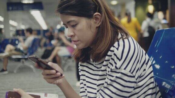 一名亚洲女性在机场使用智能手机