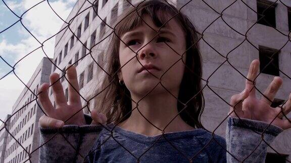 无家可归的孩子孤独的孩子躲在篱笆后面
