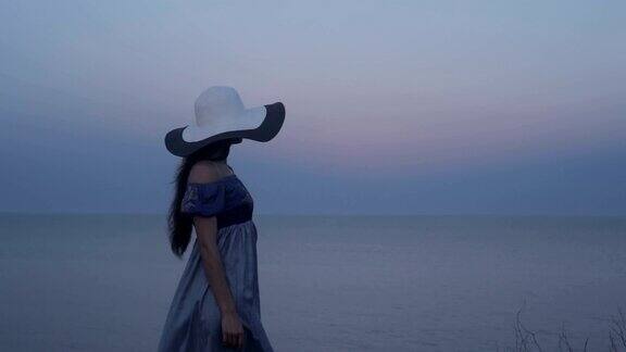 戴帽子的女孩在海边看日落