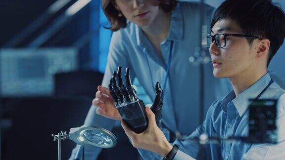 技术假肢机器人手臂是由两位专业开发工程师测试在一个高科技研究实验室与现代未来的设备男性和女性比较个人电脑上的数据