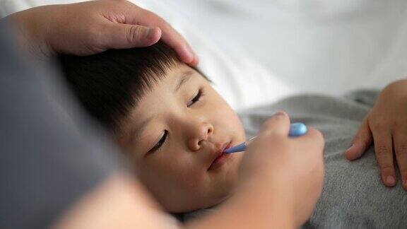 亚洲孩子感到恶心的温度计和母亲照顾和生病