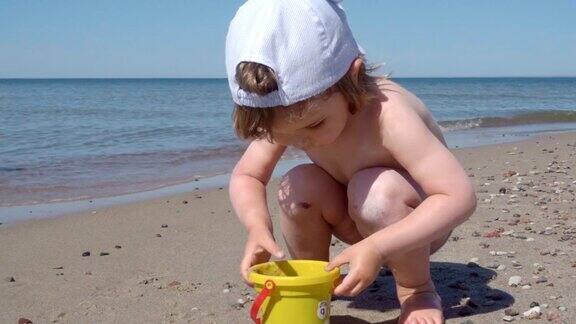 金发小男孩在海边玩耍孩子在海边的沙滩上走着玩着沙子和玩具