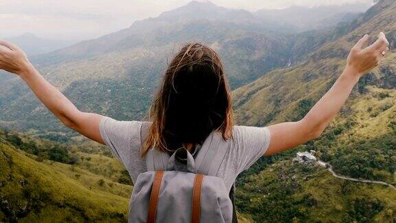 近距离的后视图兴奋的年轻女游客与背包张开双臂看史诗般的斯里兰卡山脉风景