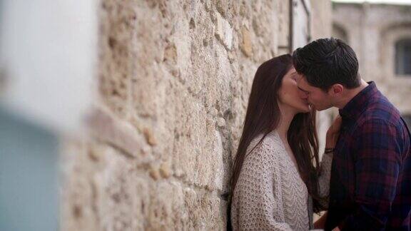 一对年轻情侣在石墙前接吻
