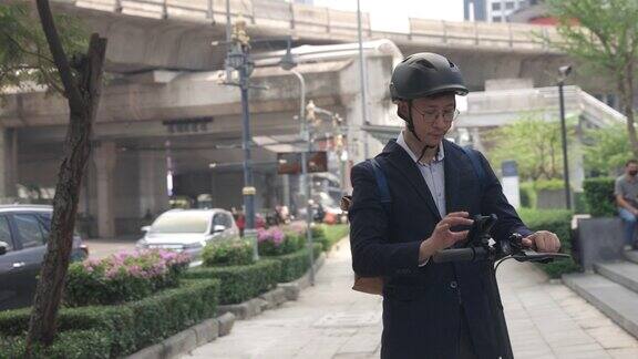 亚洲男子在大城市使用手机和骑电动滑板车