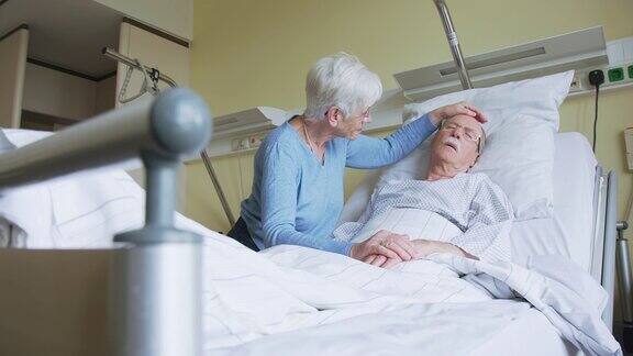 老年妇女在病床上安慰不安的丈夫