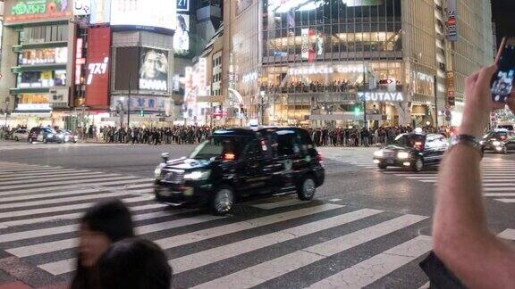 在日本东京许多行人和车辆在夜间穿过路口的涩谷十字路口