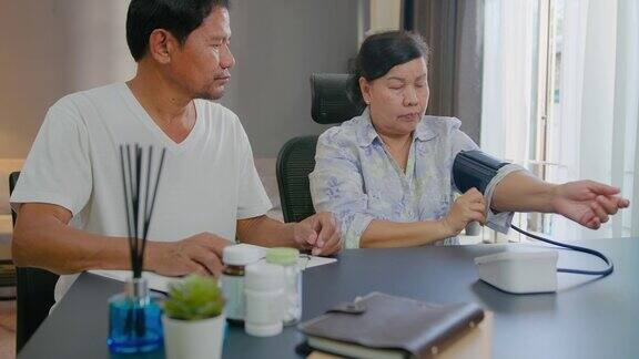 一对亚洲老年夫妇在家检查血压和心率