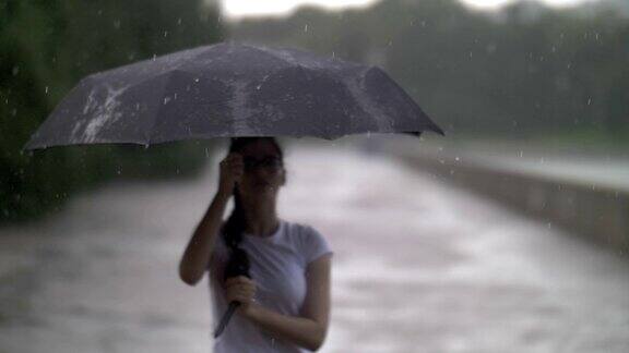女孩在雨天里捻着伞看着雨点打在伞上秋天的心情慢动作