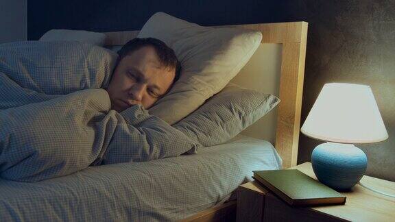 人有失眠症晚上躺在床上睡不着床头桌上的灯就开着