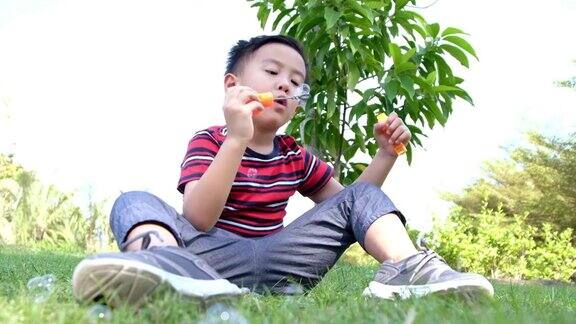 一个男孩在玩泡泡快乐的孩子在春天的公园吹肥皂泡