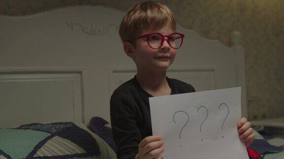 可爱的学龄前儿童戴着眼镜拿着一张写着问号的纸找到解决问题的方法