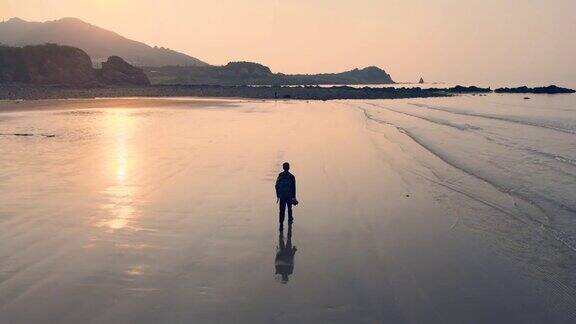 日出时在海滩上散步的人