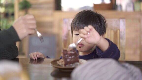 亚洲母亲和男婴在蛋糕店吃巧克力蛋糕