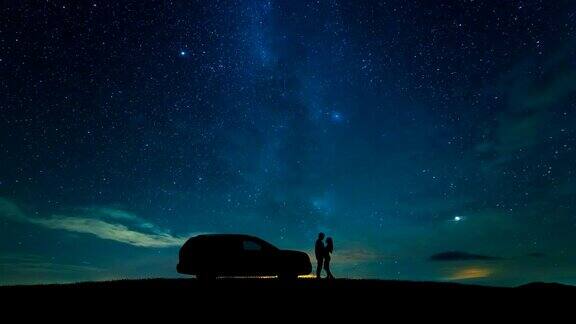 这对情侣站在一辆汽车旁背景是星空时间流逝