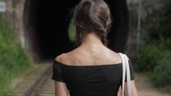 女孩穿着露肩t恤走在旧的棕色铁路
