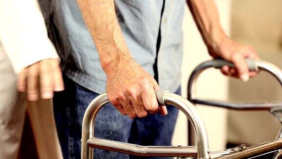 女医生帮助老年男性病人使用助行器手牵手