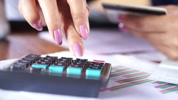 商务妇女手计算计算器使用她的信用卡在网上购物