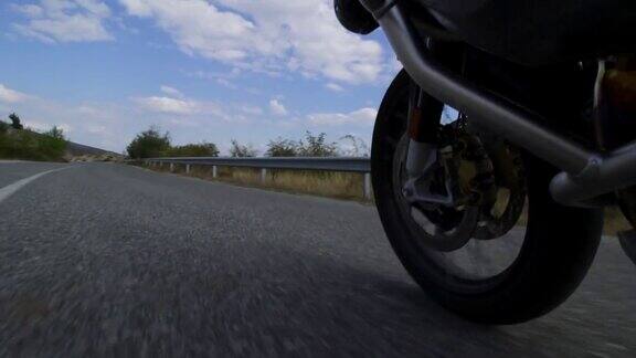 在自然的道路上骑摩托车在颠簸的柏油路上靠近车轮记录在100帧每秒