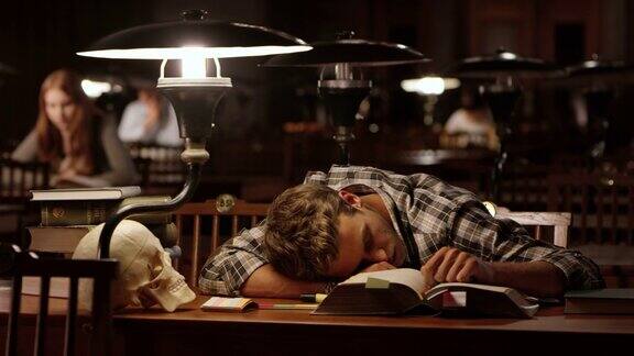 年轻的医科男学生在图书馆睡着了
