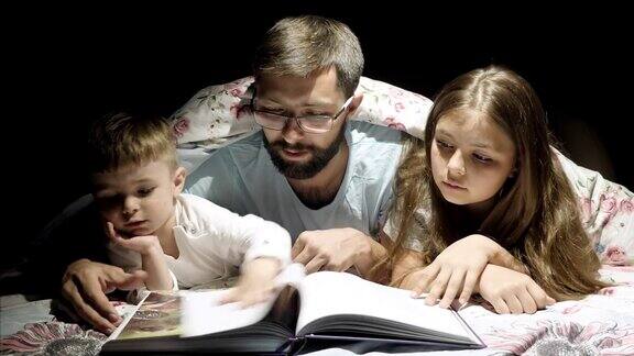 慈爱的父亲在晚上给孩子们读童话故事