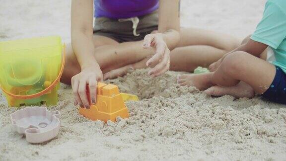 快乐的男孩和他的妈妈在沙滩上玩沙子和快乐
