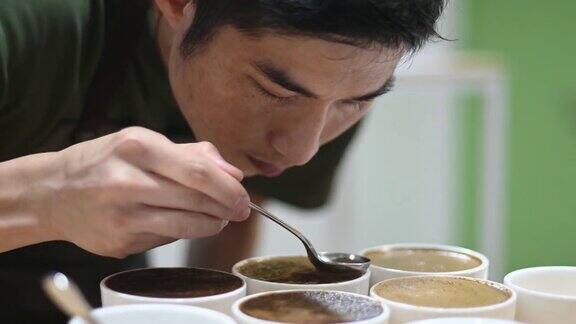 专业的亚洲华人男性咖啡师正在进行拔杯弯下腰仔细闻每一个咖啡样品