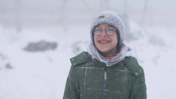 一个十几岁的男孩在冬天的风雪中大笑的肖像